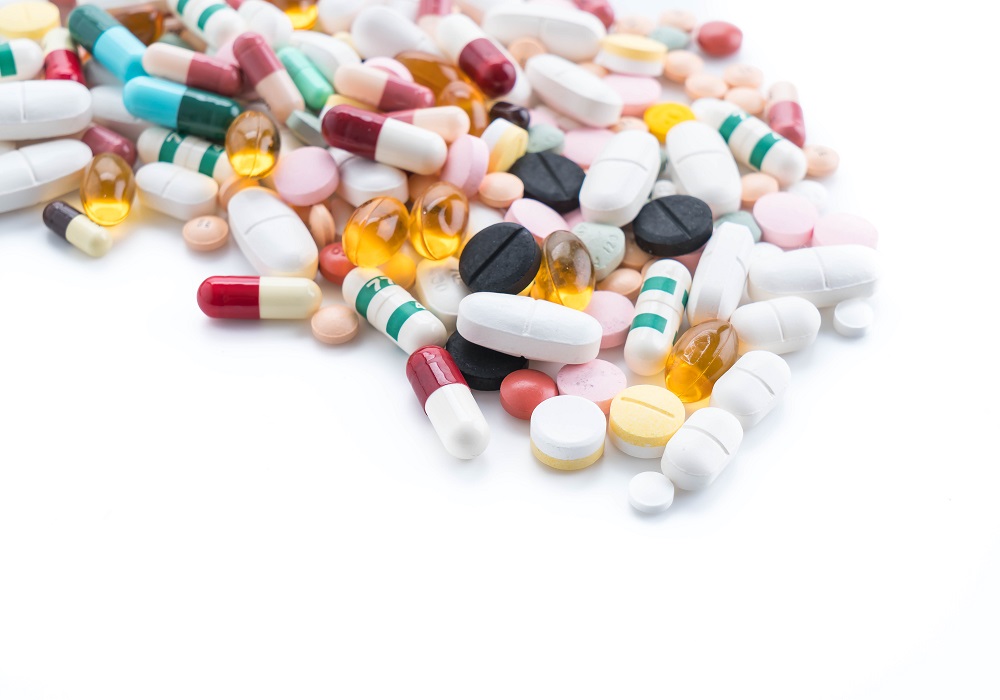 packings of pills and capsules of medicines on white background